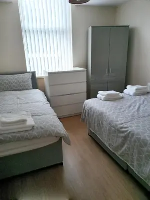 a bedroom with two beds and a dresser and a cabinet at Sandringham House in Liverpool