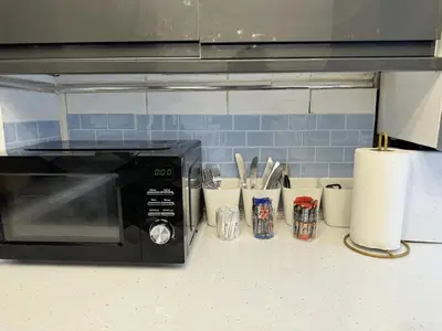 a kitchen counter with a black microwave and utensils at 4 Bedroom Anfield House, 7 beds, Free Parking, Garden - 5 mins to LFC, 15 mins to City Centre in Liverpool