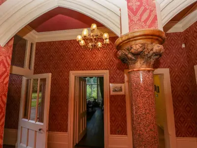 a room with a chandelier and a column in a house at Millwood Manor in Barrow in Furness