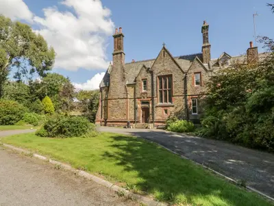 an old stone house with a driveway in front of it at Millwood Manor in Barrow in Furness
