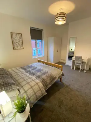 a bedroom with a bed and a table and chairs at A spacious & modern 3-bed home in Blackburn