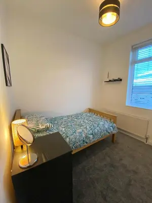 a bedroom with a bed and a desk and a window at A spacious & modern 3-bed home in Blackburn