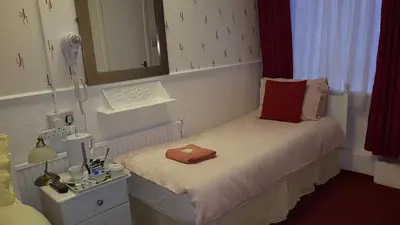 a small bedroom with a bed with a mirror at The Brema Hotel in Blackpool