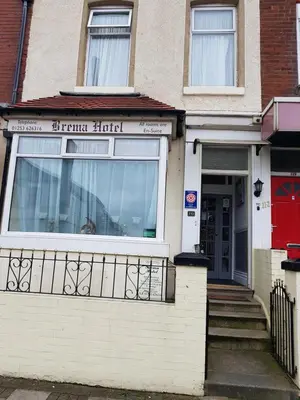 a white brick house with a red door at The Brema Hotel in Blackpool