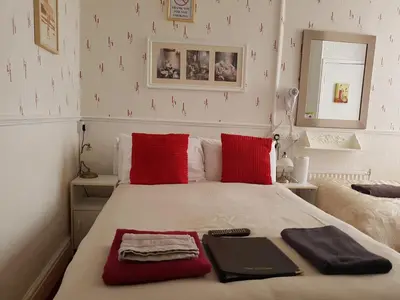 a bedroom with a bed with red pillows and a laptop on it at The Brema Hotel in Blackpool