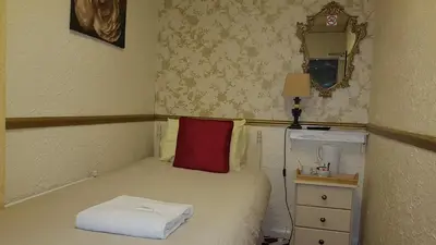 a small bedroom with a bed with a red pillow at The Brema Hotel in Blackpool