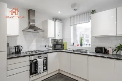 a white kitchen with white cabinets and appliances at Stylish 3-Bed Sleeps 8 Liverpool free wifi carpark By Hinkley Homes Short Lets & Serviced Accommodation in Liverpool