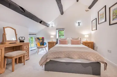 a bedroom with a bed and a desk and a mirror at Bluebell Wood Cottage - with hot tub in Cartmel