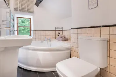 a bathroom with a tub and a toilet and a sink at Bluebell Wood Cottage - with hot tub in Cartmel
