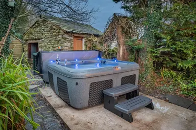 a large bath tub sitting in a yard at Bluebell Wood Cottage - with hot tub in Cartmel