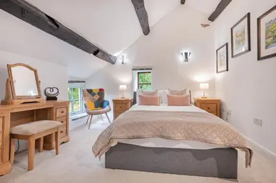 a bedroom with a bed and a desk and a mirror at Bluebell Wood Cottage - with hot tub in Cartmel