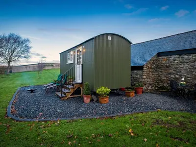 a green tiny house sitting on top of a yard at The Pleasant Hut at Mount Pleasant Farm in Ulverston