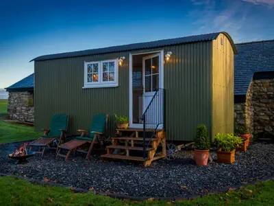 a green tiny house with chairs and a patio at The Pleasant Hut at Mount Pleasant Farm in Ulverston
