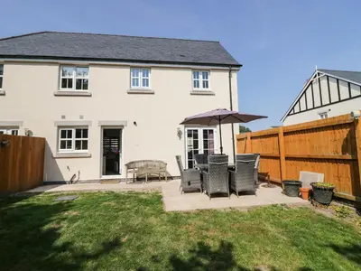 a house with a patio with chairs and an umbrella at Rolo's Retreat in Grange Over Sands