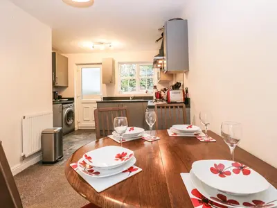 a kitchen and dining room with a wooden table with wine glasses at Rolo's Retreat in Grange Over Sands