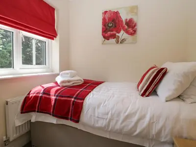 a bedroom with a bed with a red and white blanket at Rolo's Retreat in Grange Over Sands