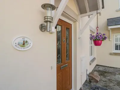 a door to a house with a sign on the wall at Rolo's Retreat in Grange Over Sands