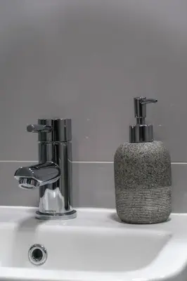 a bathroom sink with a soap dispenser next to two faucets at The V.I.P Suite - Sleeps 24! Best for large groups in Liverpool