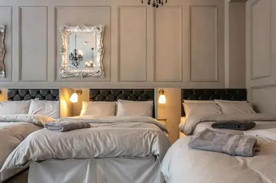 a room with three beds with a mirror on the wall at The V.I.P Suite - Sleeps 24! Best for large groups in Liverpool