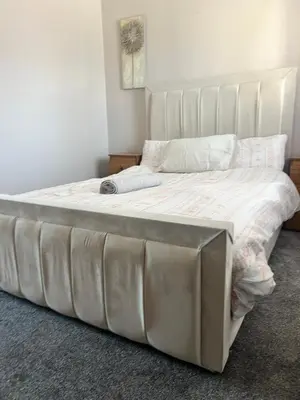 a bed with a large white bed frame in a bedroom at Home Away in Wigan