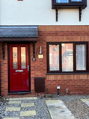 a brick house with a red door and windows at Home Away in Wigan