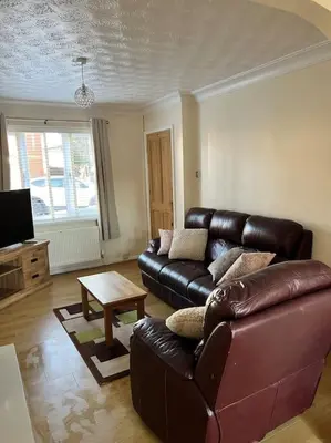 a living room with a leather couch and a table at Home Away in Wigan