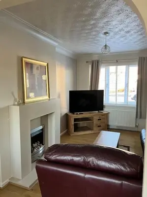 a living room with a leather couch and a fireplace at Home Away in Wigan