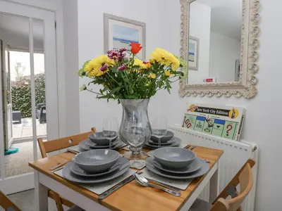 a dining room table with a vase of flowers on it at The Bay Cottage - Morecambe Bay in Morecambe
