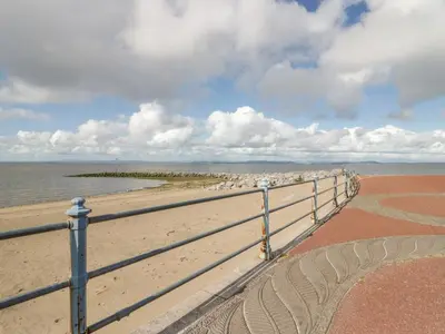 a fence on a beach with a flock of birds at The Bay Cottage - Morecambe Bay in Morecambe