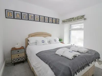 a white bedroom with a large bed with two pillows at The Bay Cottage - Morecambe Bay in Morecambe