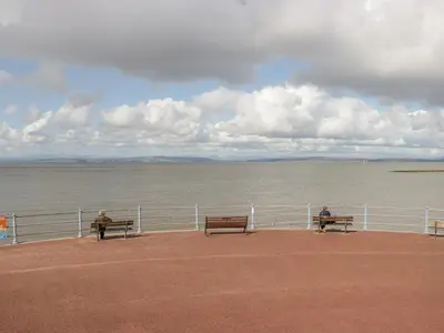 two people sitting on benches looking at the water at The Bay Cottage - Morecambe Bay in Morecambe