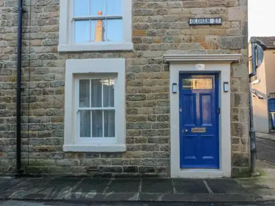a brick building with a blue door and a window at The Bay Cottage - Morecambe Bay in Morecambe