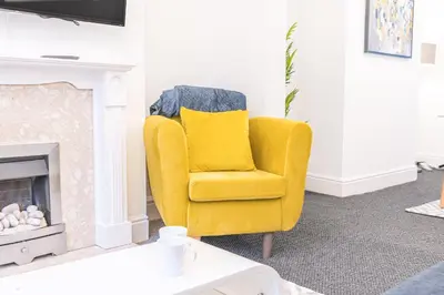 a yellow chair in a living room with a fireplace at *King Bed* Comfy City House in Barrow in Furness