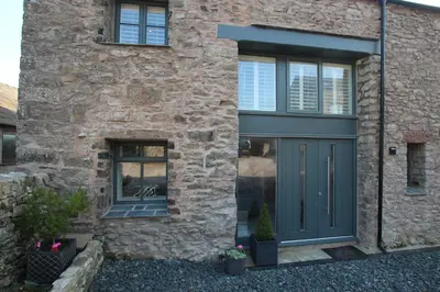 a stone house with a blue door and a window at Hideaway in Great Urswick