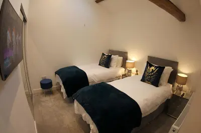 two twin beds in a room with two lamps at Hideaway in Great Urswick