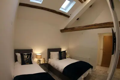 two beds in a room with two windows at Hideaway in Great Urswick