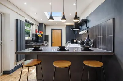 a kitchen with a bar with three stools at Wrights Terrace - Air Host and Stay - 4 Bedroom in Liverpool
