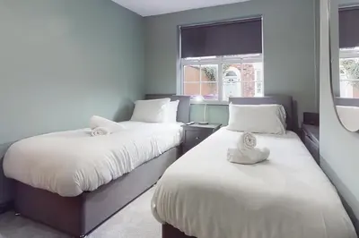 two beds in a room with two windows at Wrights Terrace - Air Host and Stay - 4 Bedroom in Liverpool