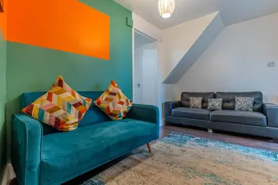 a living room with a blue couch and an orange wall at 