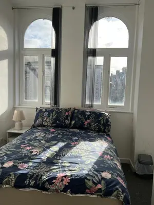 a bedroom with a bed with a floral bedspread and two windows at 2 bedroom city centre apartment 35 Victoria street in Liverpool