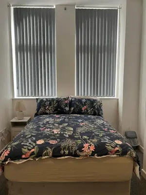 a bedroom with a bed with a floral bedspread and two windows at 2 bedroom city centre apartment 35 Victoria street in Liverpool