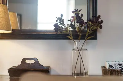a vase of flowers sitting on a table in front of a mirror at Smart self-catering apartment, Clitheroe in Clitheroe