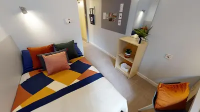 a small room with a bed with colorful pillows at iQ Great Newton House in Liverpool in Liverpool