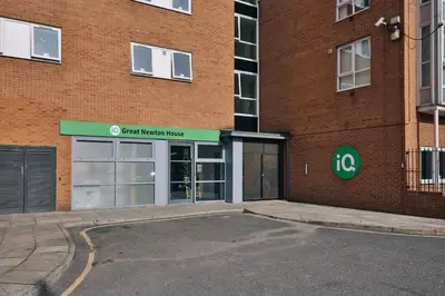 a large brick building with a green sign on it at iQ Great Newton House in Liverpool in Liverpool