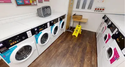 a laundry room with three washing machines and a wooden floor at iQ Great Newton House in Liverpool in Liverpool