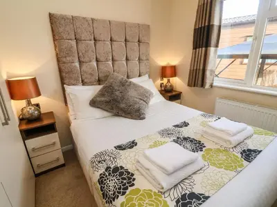 a bedroom with a bed and two lamps and a window at Dream Catcher Lodge in Carnforth