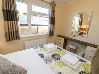 a bedroom with a bed and a mirror and a window at Dream Catcher Lodge in Carnforth