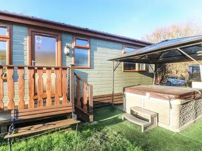 a small house with a hot tub and an umbrella at Dream Catcher Lodge in Carnforth