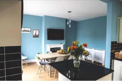a kitchen with blue walls and a table with a vase of flowers at Spacious Family Home Minutes from the Beach in Blackpool