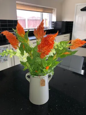 a white vase filled with orange flowers on a counter at Spacious Family Home Minutes from the Beach in Blackpool